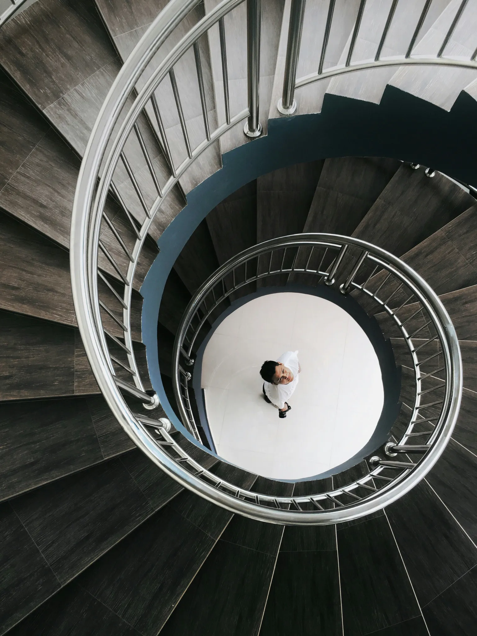 Man looking up from the ground with a spiral staircase around him